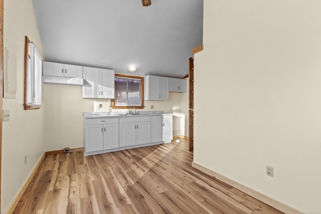 kitchen featuring white cabinets, light wood-type flooring, and sink