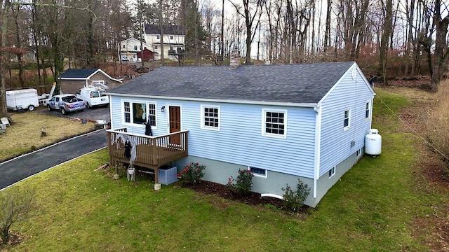 view of front of property with a deck, a front lawn, and central air condition unit