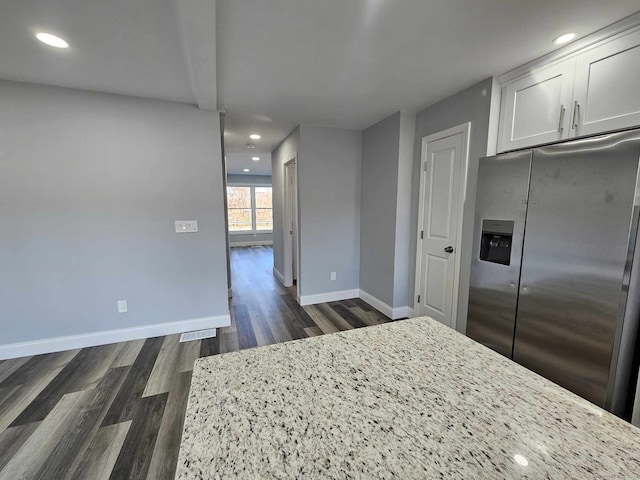 kitchen with white cabinets, dark hardwood / wood-style flooring, stainless steel fridge, and light stone counters