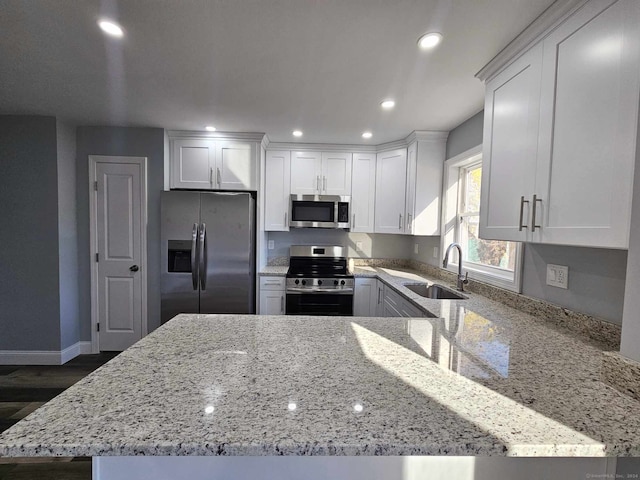 kitchen featuring sink, stainless steel appliances, light stone counters, dark hardwood / wood-style flooring, and white cabinets