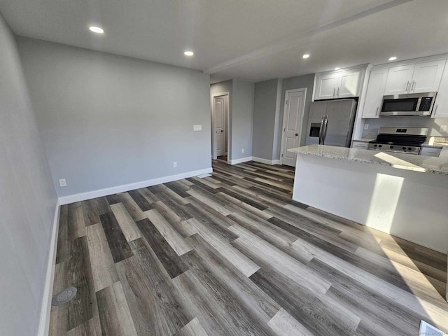 kitchen featuring dark hardwood / wood-style floors, light stone countertops, white cabinetry, and appliances with stainless steel finishes