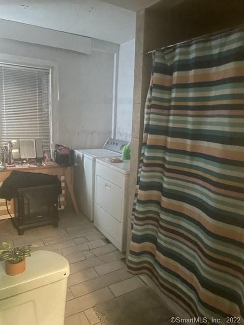 bathroom with curtained shower and separate washer and dryer