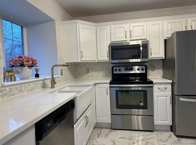 kitchen with white cabinets, appliances with stainless steel finishes, and backsplash