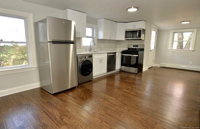 kitchen featuring appliances with stainless steel finishes, washer / dryer, and a healthy amount of sunlight