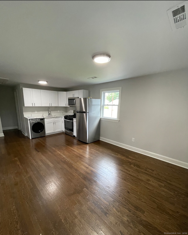 kitchen with stainless steel appliances, dark wood-type flooring, sink, washer / clothes dryer, and white cabinetry