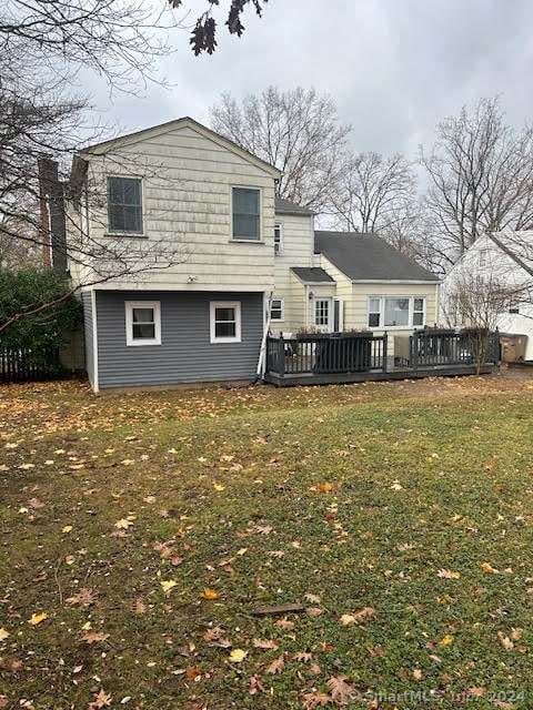 back of property with a yard and a wooden deck