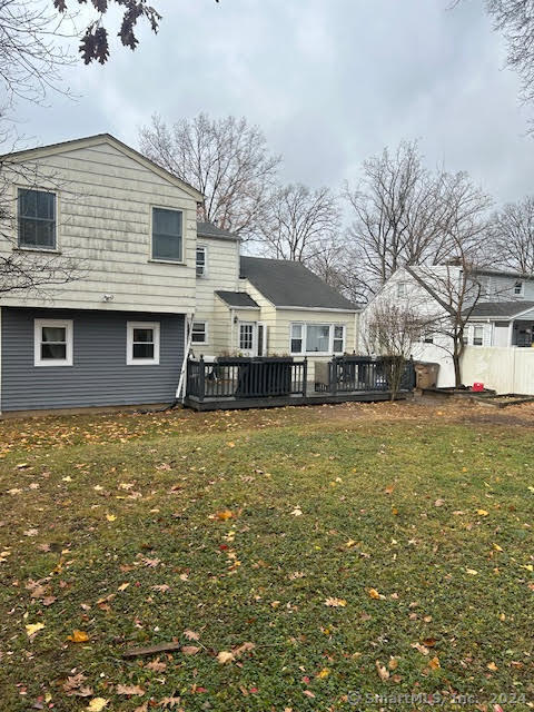 rear view of house featuring a lawn and a deck