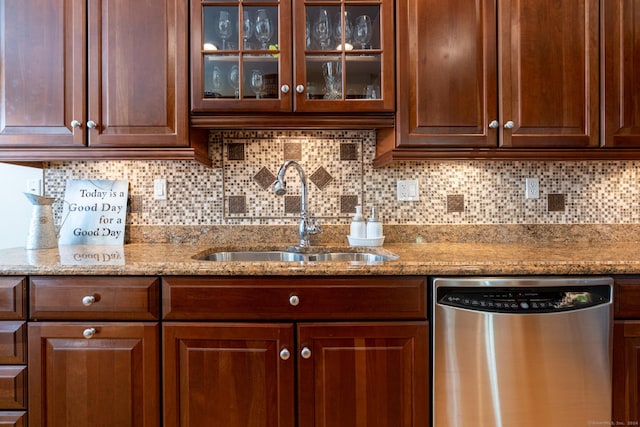 kitchen with light stone countertops, decorative backsplash, sink, and stainless steel dishwasher