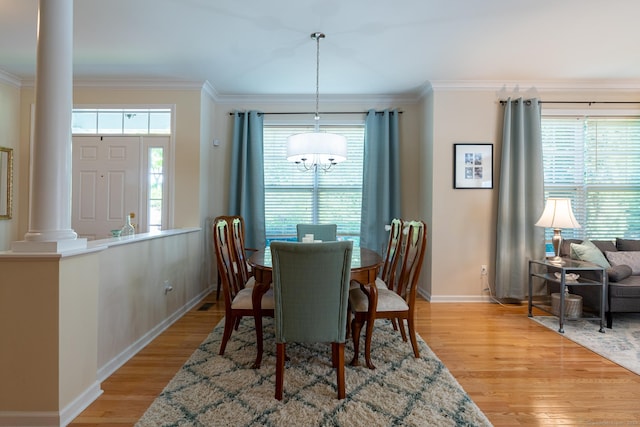 dining room with decorative columns, crown molding, light hardwood / wood-style flooring, and a chandelier