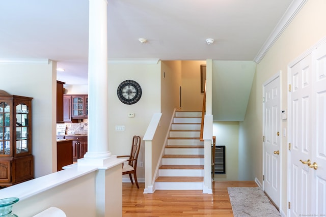 stairs featuring hardwood / wood-style floors, ornamental molding, and decorative columns