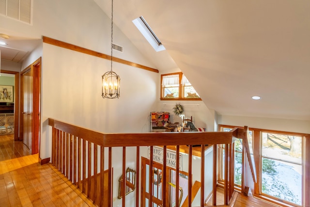 hallway featuring a healthy amount of sunlight, light hardwood / wood-style floors, and lofted ceiling