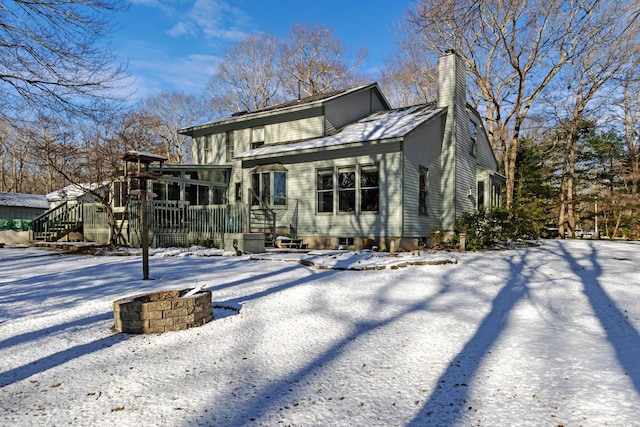 snow covered property with a fire pit and a sunroom