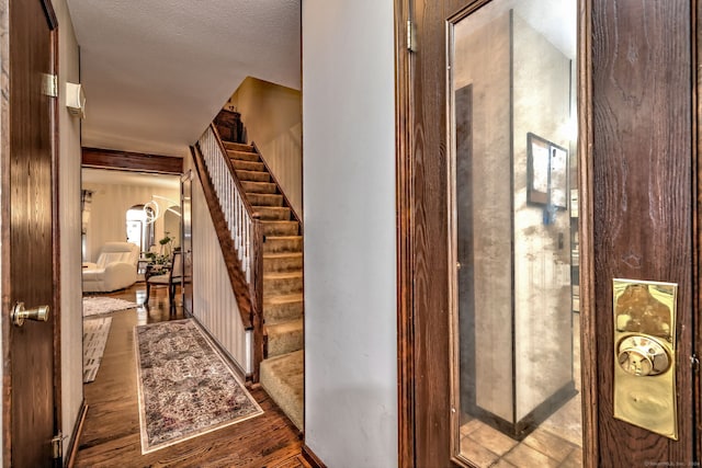 stairs with hardwood / wood-style floors and a textured ceiling