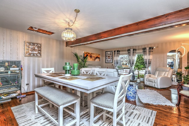 dining area featuring a chandelier, beamed ceiling, and dark wood-type flooring