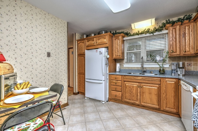 kitchen with a textured ceiling, white appliances, and sink