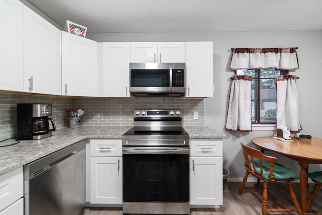 kitchen featuring white cabinets, appliances with stainless steel finishes, and light stone counters