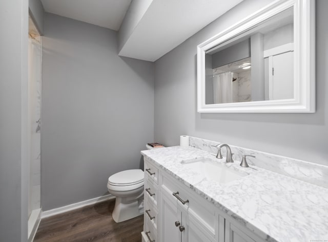 bathroom with walk in shower, hardwood / wood-style floors, vanity, and toilet