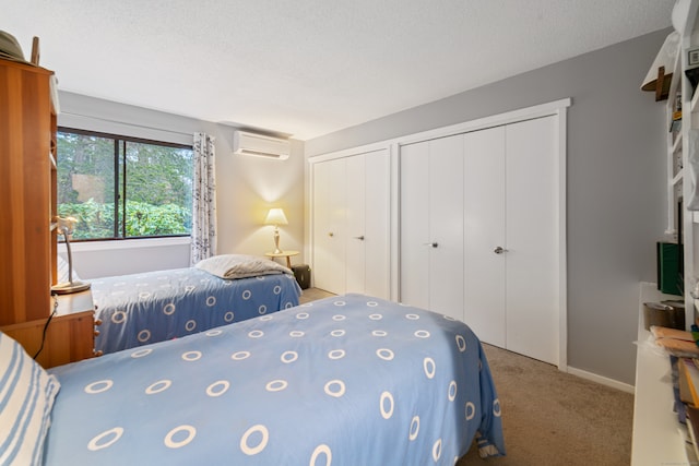 bedroom with an AC wall unit, two closets, carpet floors, and a textured ceiling