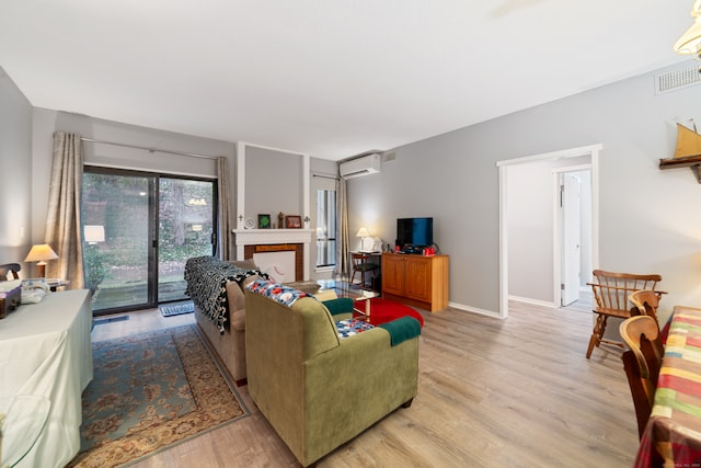 living room with a wall mounted AC and light hardwood / wood-style floors