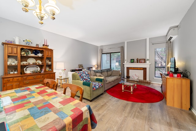 dining space with a wall mounted AC, light hardwood / wood-style flooring, plenty of natural light, and a fireplace