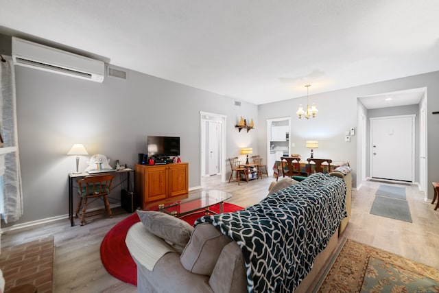 living room with light hardwood / wood-style flooring, a wall mounted air conditioner, and a notable chandelier