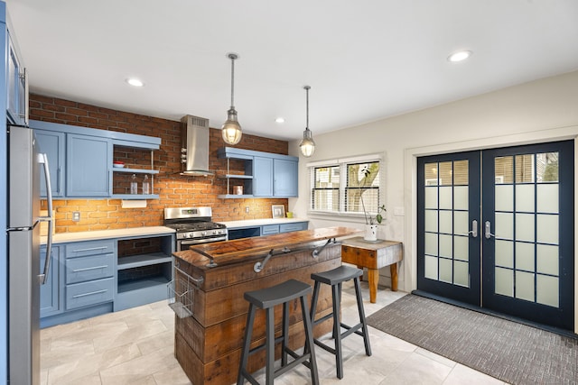 kitchen featuring wall chimney range hood, blue cabinetry, appliances with stainless steel finishes, and french doors