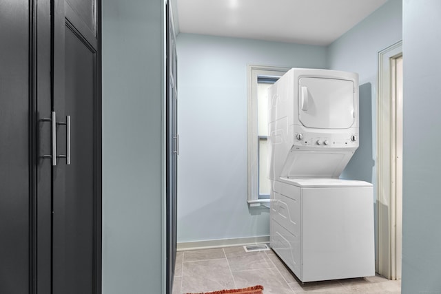 washroom with light tile patterned flooring and stacked washer / drying machine