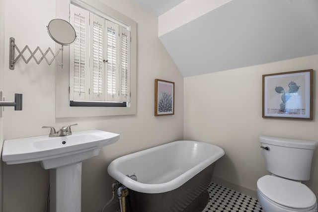 bathroom with a bathing tub, sink, vaulted ceiling, tile patterned flooring, and toilet