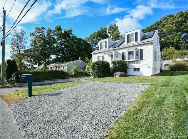 cape cod-style house with solar panels and a front lawn