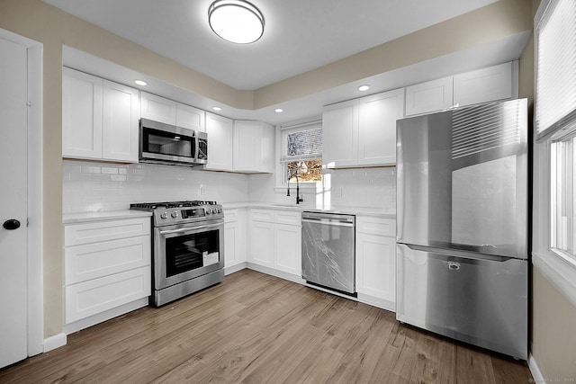 kitchen with stainless steel appliances, white cabinetry, sink, and tasteful backsplash