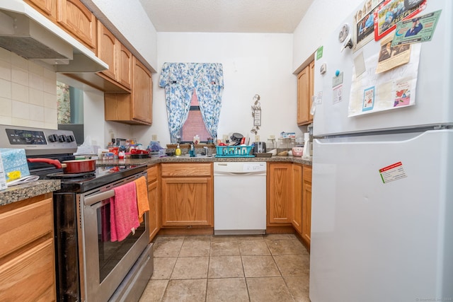 kitchen featuring a textured ceiling, light tile patterned flooring, white appliances, and backsplash