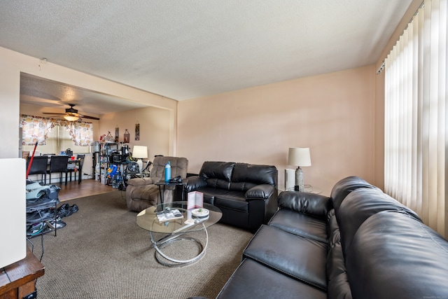 living room featuring ceiling fan, wood-type flooring, and a textured ceiling