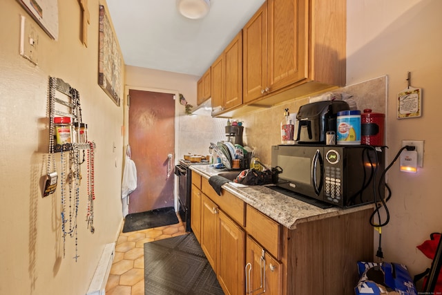 kitchen featuring black appliances, tile patterned floors, and tasteful backsplash