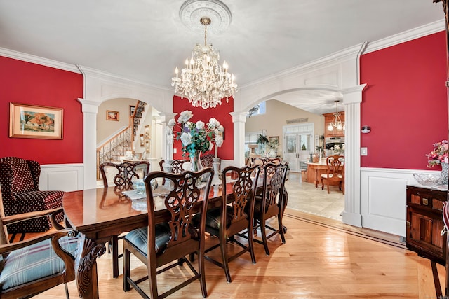 dining area with light hardwood / wood-style floors, ornate columns, and crown molding