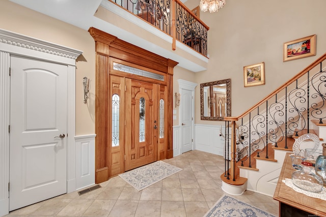 foyer entrance featuring light tile patterned floors, a high ceiling, and a notable chandelier