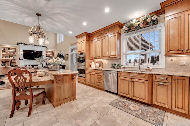 kitchen featuring stainless steel appliances, sink, decorative light fixtures, an inviting chandelier, and a center island