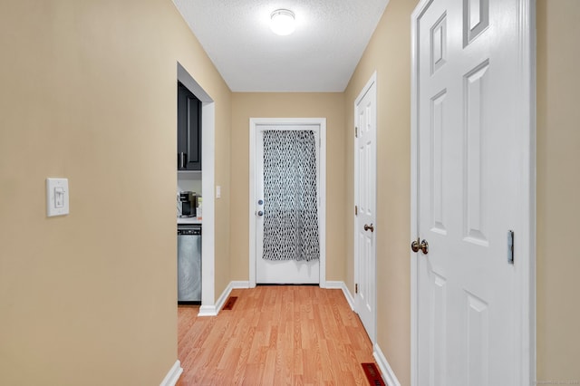 hallway with a textured ceiling and light wood-type flooring