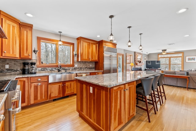 kitchen with appliances with stainless steel finishes, hanging light fixtures, sink, and a kitchen island