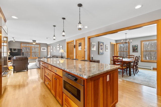 kitchen featuring hanging light fixtures, a center island, light stone counters, light hardwood / wood-style floors, and a baseboard radiator