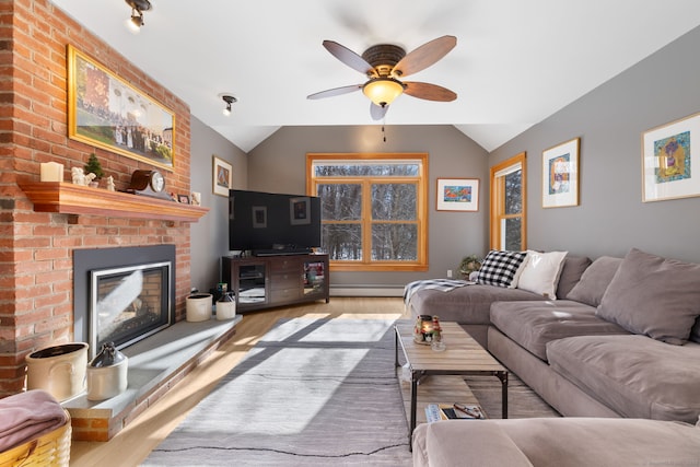 living room featuring a baseboard heating unit, a fireplace, vaulted ceiling, and light wood-type flooring