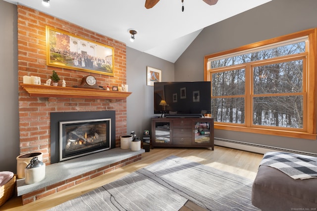 living room featuring lofted ceiling, hardwood / wood-style flooring, ceiling fan, baseboard heating, and a brick fireplace