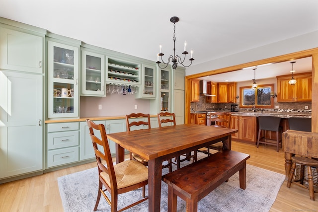 dining room featuring an inviting chandelier, sink, and light hardwood / wood-style flooring