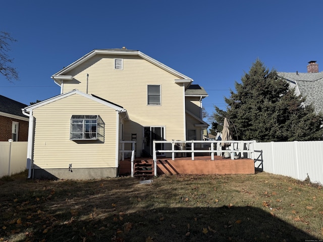 rear view of property featuring a wooden deck and a lawn