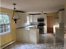 kitchen featuring baseboard heating, kitchen peninsula, pendant lighting, white cabinets, and appliances with stainless steel finishes