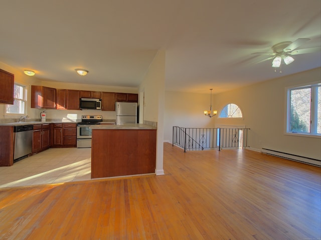 kitchen featuring stainless steel appliances, baseboard heating, pendant lighting, light hardwood / wood-style floors, and ceiling fan with notable chandelier