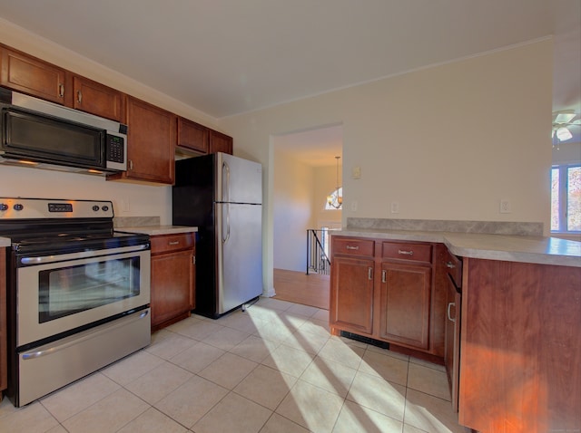 kitchen featuring light tile patterned floors, stainless steel appliances, and a notable chandelier