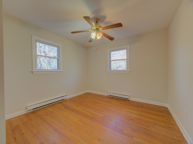 empty room featuring plenty of natural light, light hardwood / wood-style flooring, and a baseboard heating unit