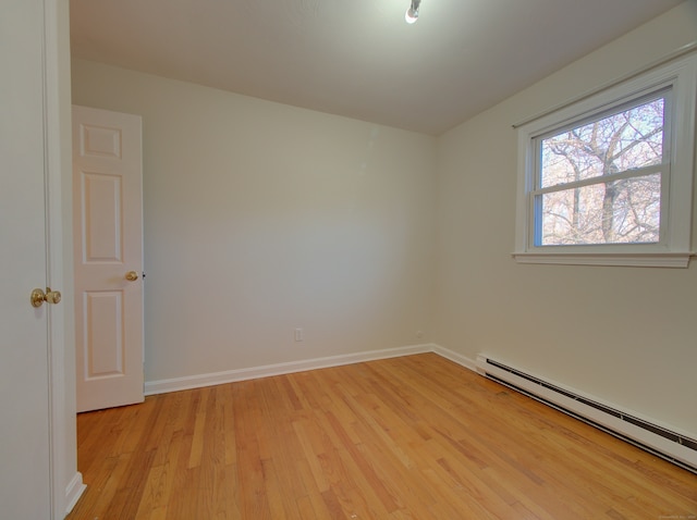 unfurnished room featuring light hardwood / wood-style flooring and a baseboard heating unit