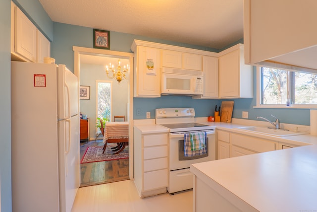 kitchen with white cabinetry, sink, an inviting chandelier, light hardwood / wood-style floors, and white appliances