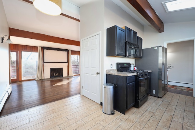 kitchen with black appliances, a large fireplace, light hardwood / wood-style floors, and a baseboard heating unit